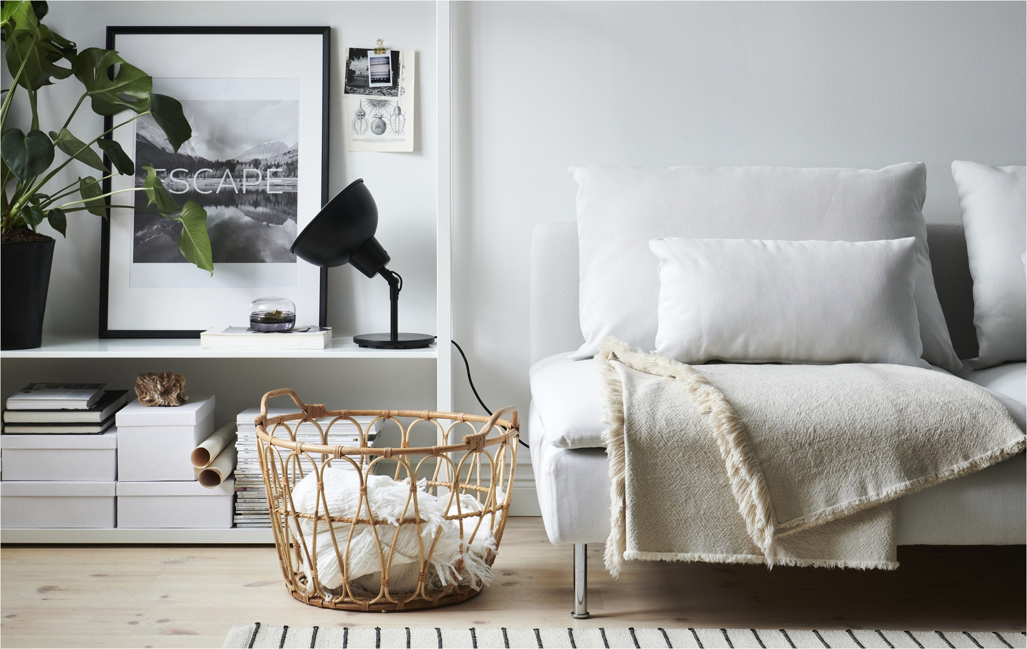 a living room with white sofa black lamp open storage unit and wicker basket